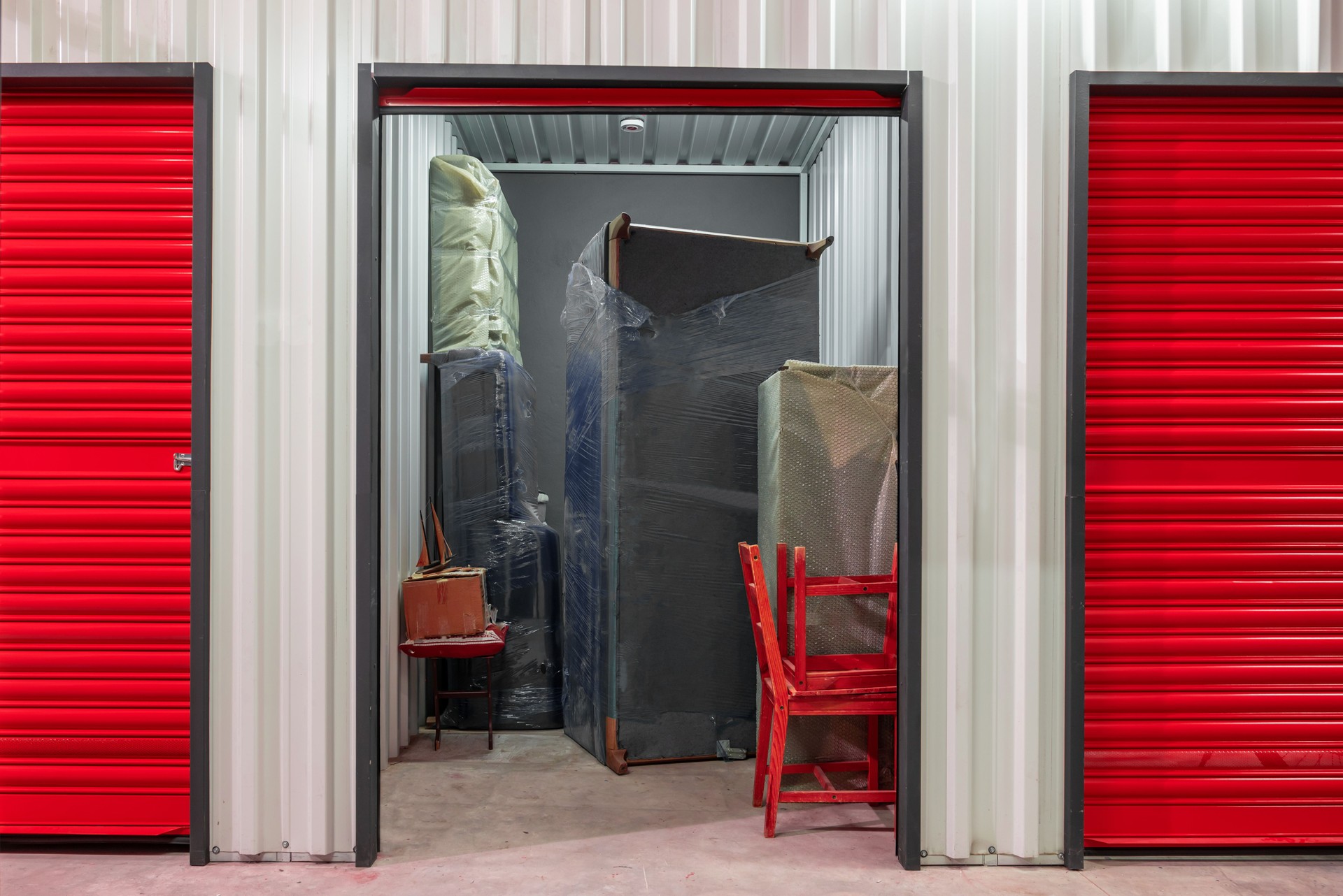 Pasillo de unidad de self storage con puertas rojas. Trasteros de alquiler