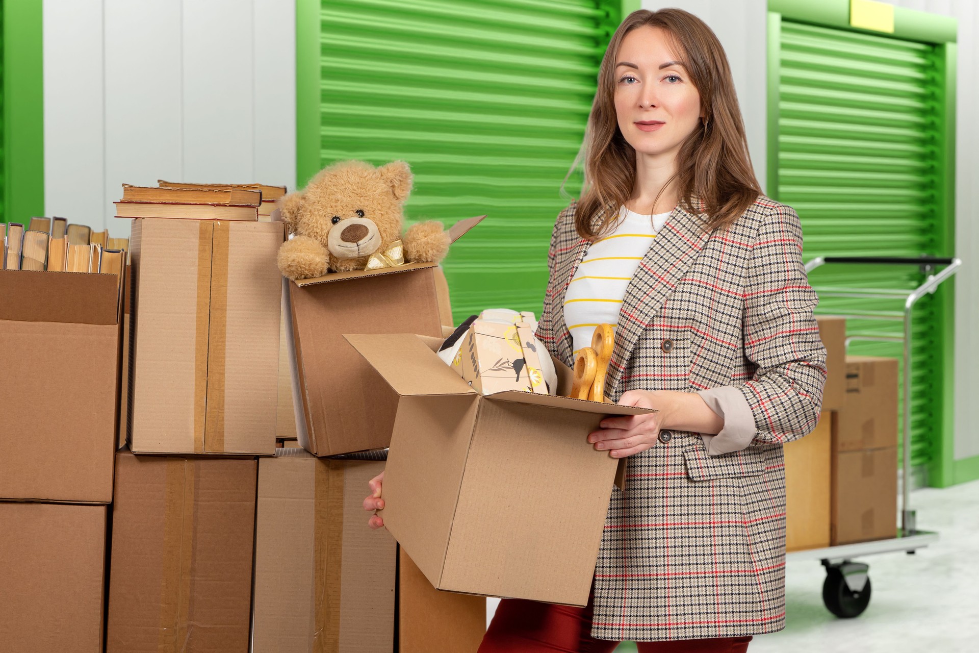 La mujer alquila una unidad de almacenamiento. Chica con objetos personales en cajas. La señora se muda a una nueva unidad de almacenamiento. Una mujer alquila un almacén. La empresaria compró artículos de la unidad de almacenamiento en una subasta. Es
